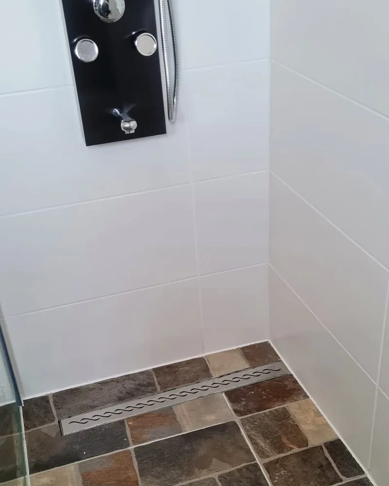 Moderne Dusche mit schwarzem Duschpaneel und Schiefermosaik-Boden von DOMIART