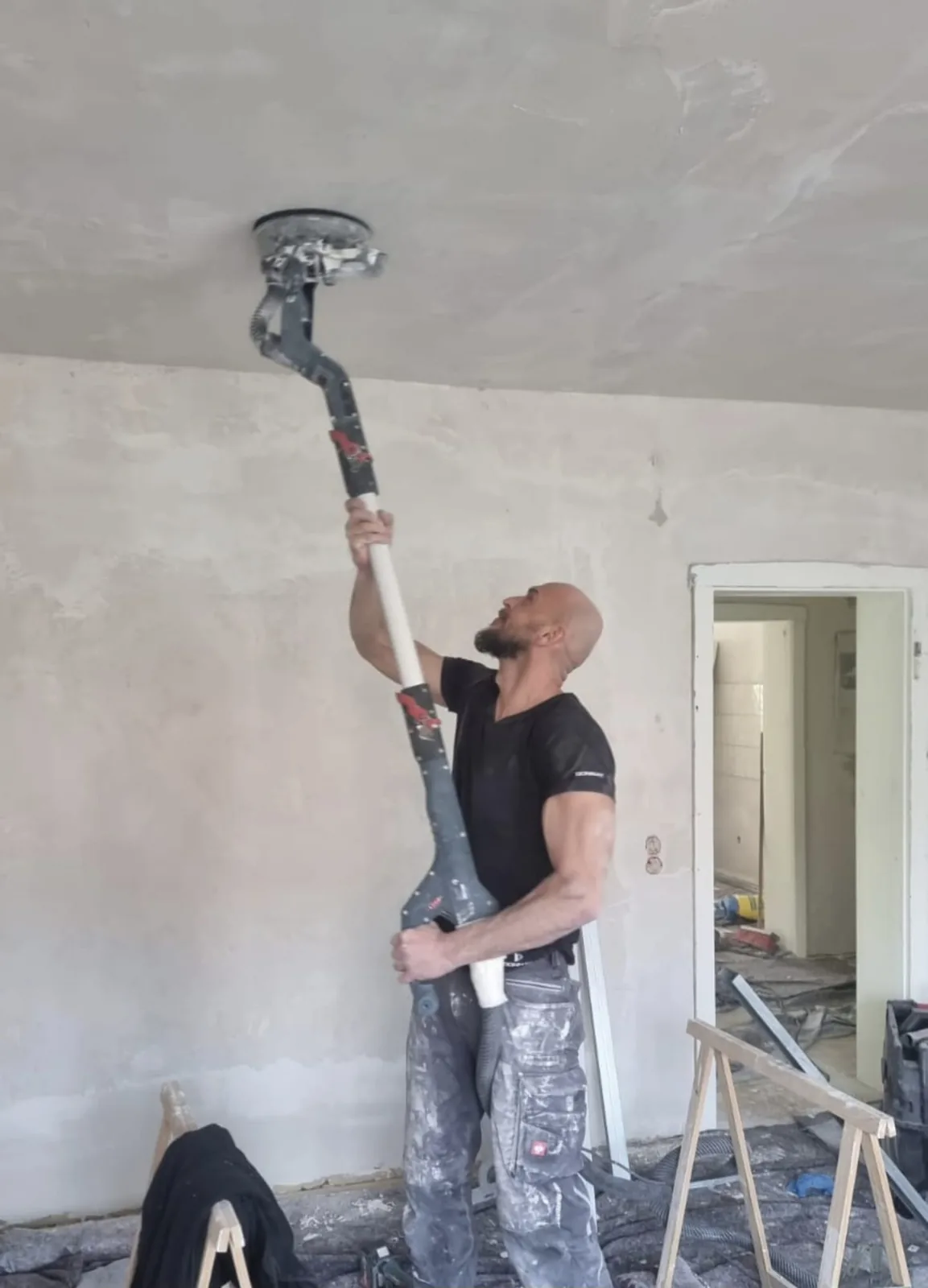 Adrian Polaczek schleift eine gespachtelte Decke mit dem Langhalsschleifer — Vorbereitung für den Anstrich