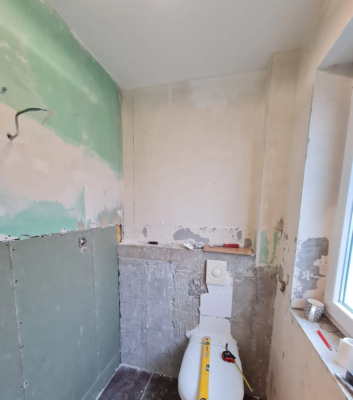 Vorwandinstallation im Bad: Ständerwerk mit grünen Feuchtraumplatten beplankt, das wandhängende WC wird mit der Wasserwaage eingerichtet