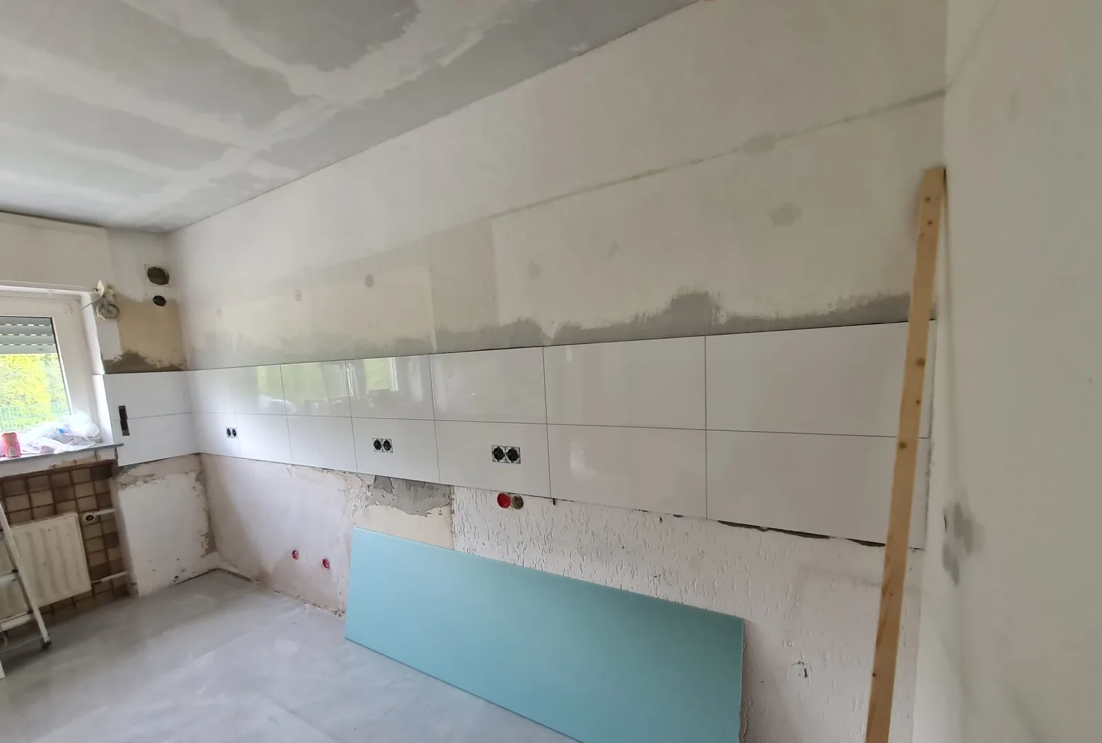 Abgehängte Trockenbaudecke, verspachtelt und bereit für den Anstrich — darunter läuft die neue Wandverfliesung auf